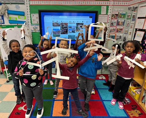 Students holding geometric shapes in art class